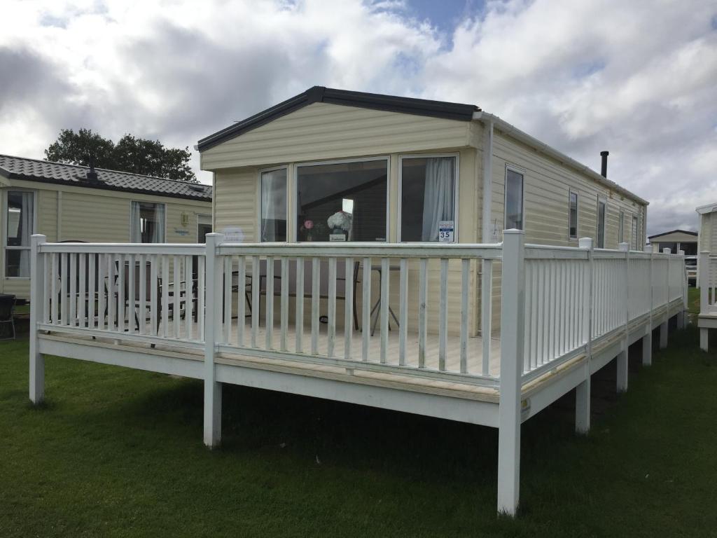 a mobile home with a white deck and a porch at Boquhanran Caravan, Whitley Bay in Hartley