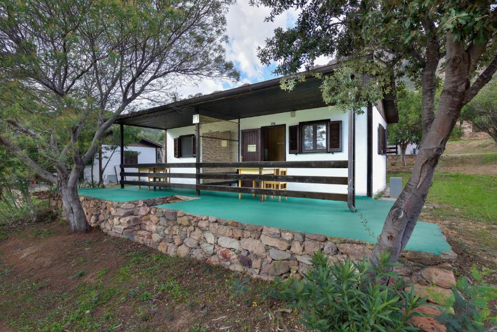 una casa con una pared de piedra delante de ella en Villaggio Camping Tesonis Beach, en Tertenìa