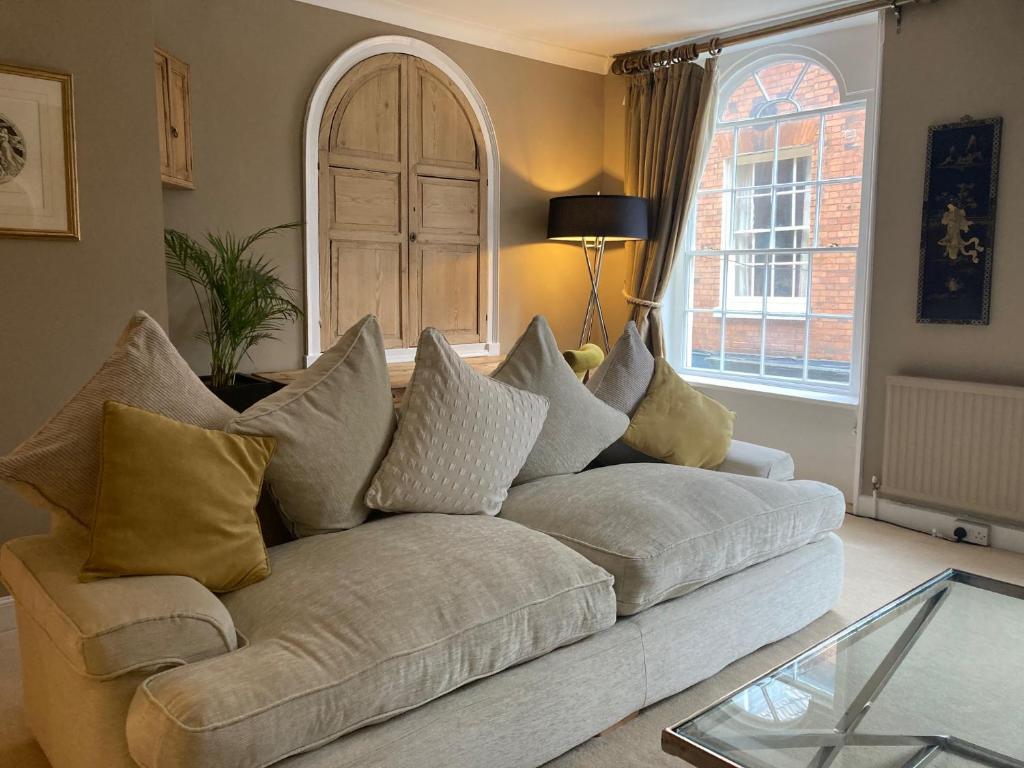 a living room with a white couch with pillows at No.25 Steep Hill - Award Winning Street, Cathedral Quarter, Lincoln - Free Parking in Lincoln