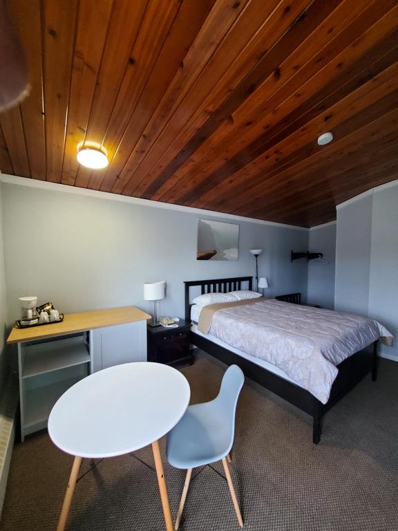 een slaapkamer met een bed en een witte tafel en stoel bij Bio Vista Motel in Wainwright