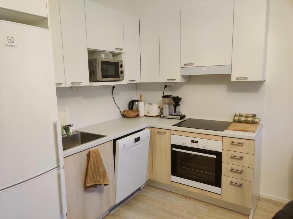 a kitchen with white cabinets and a stove top oven at Apartment near the Harbour in Turku