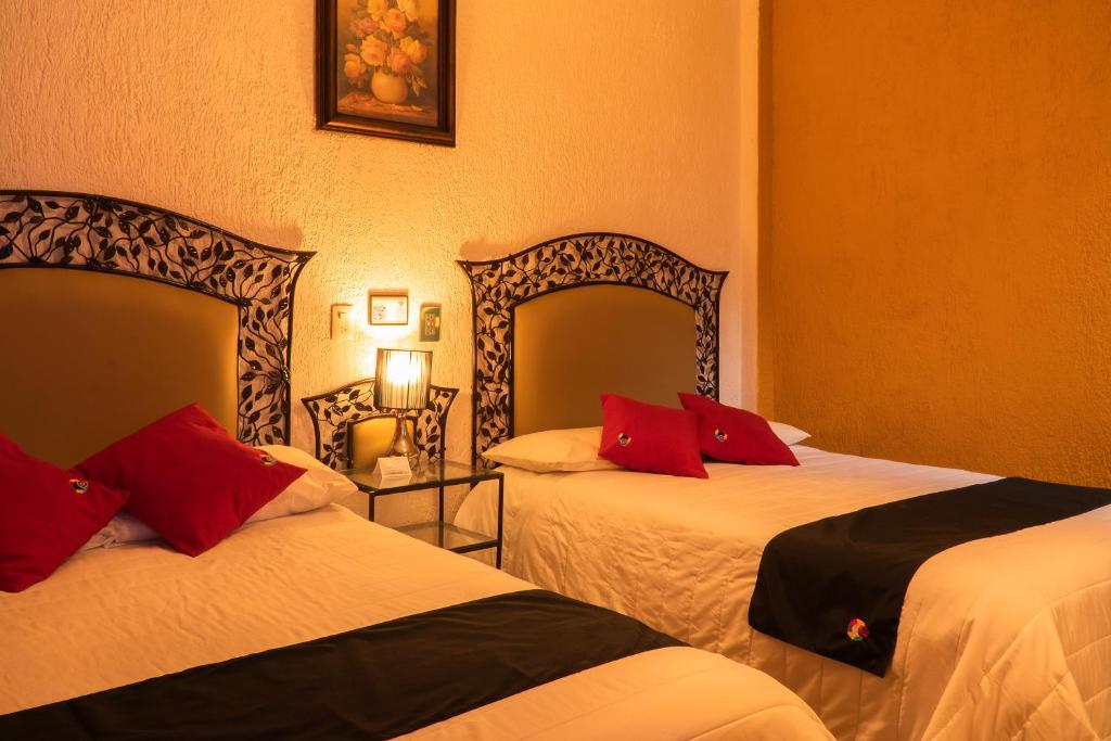 Habitación de hotel con 2 camas con almohadas rojas en Hotel Tepeyac en San Cristóbal de Las Casas