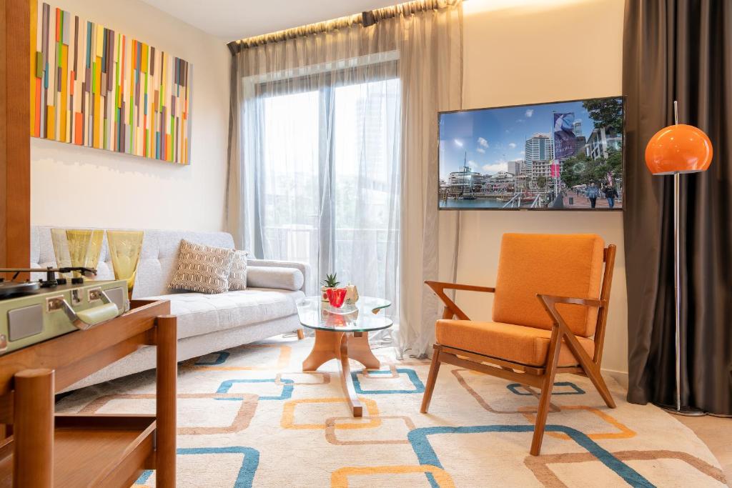 a living room with a couch and a chair at Ohtel Auckland in Auckland