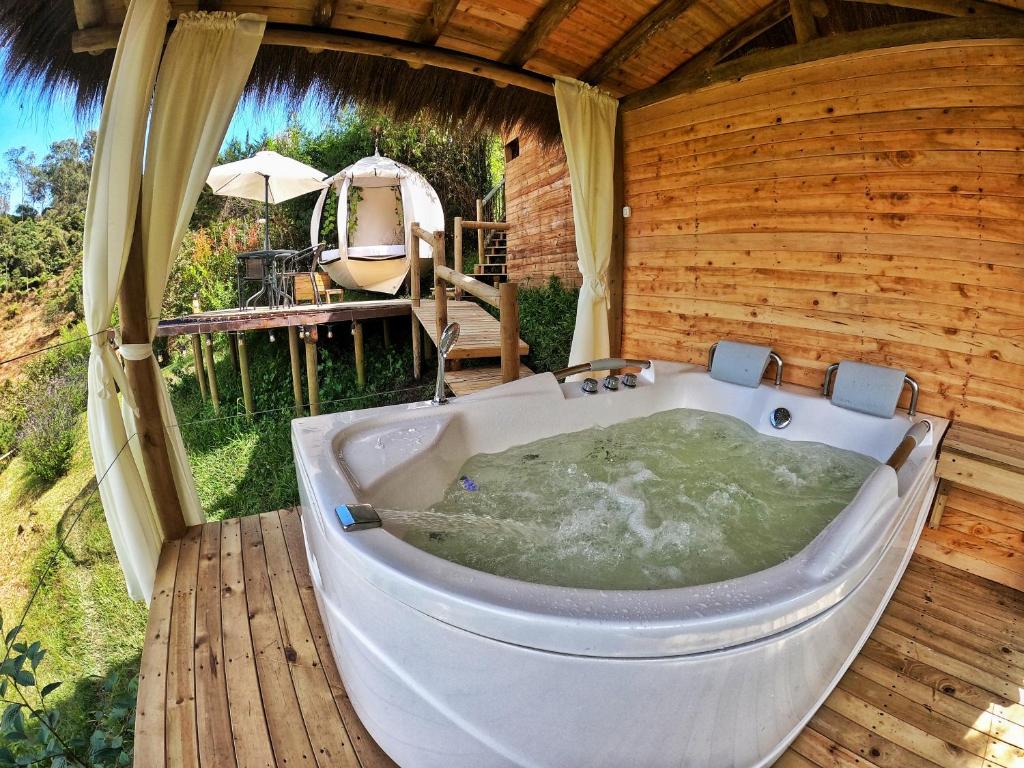 una vasca da bagno situata su una terrazza in legno in una camera di Levit Glamping - Hotel Guatapé ADULTS ONLY a Guatapé