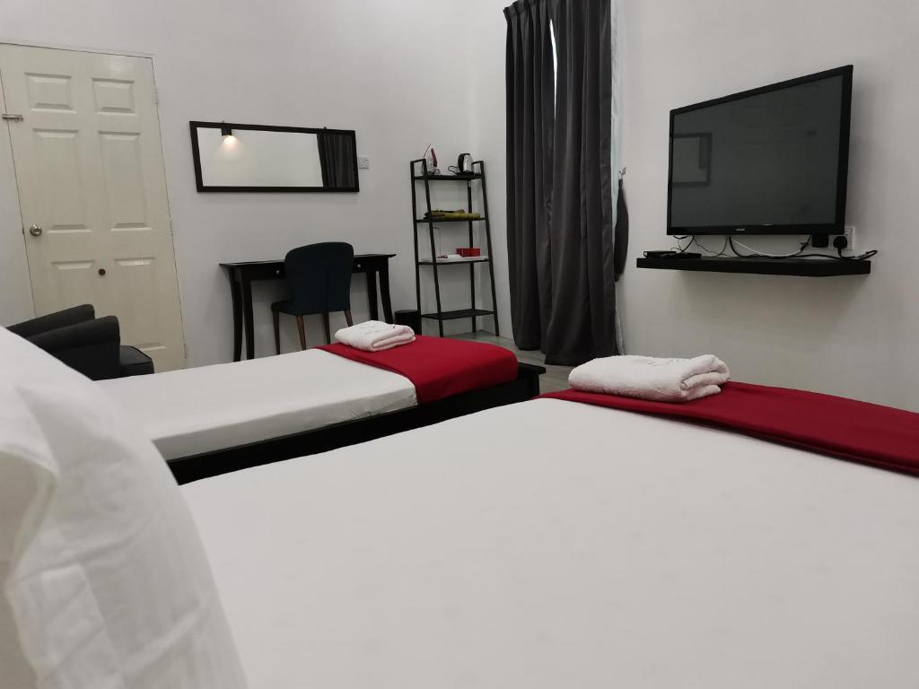 2 łóżka w pokoju z telewizorem z płaskim ekranem w obiekcie RoomStay Hj Esmon Parit Raja UTHM w mieście Parit Raja