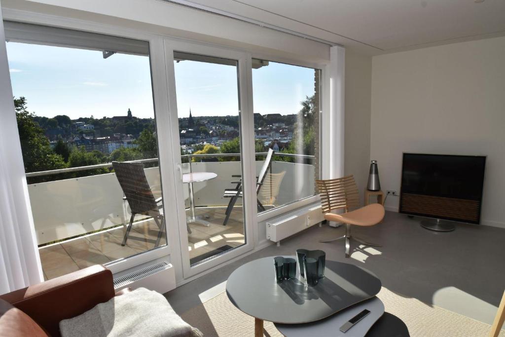 uma sala de estar com vista para uma varanda em fewo1846 - FoerdeView - luxuriöse Wohnung mit 2 Schlafzimmern und Balkon mit Hafenblick em Flensburg