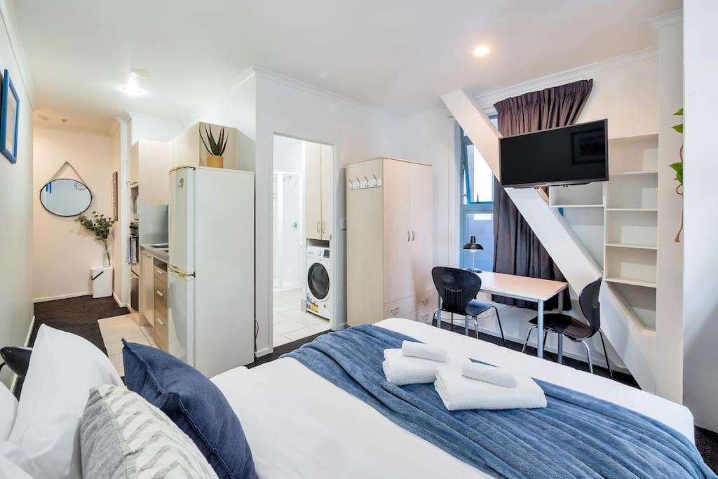 1 dormitorio con cama, escritorio y escalera en Cute Little Private Studio In the City en Auckland