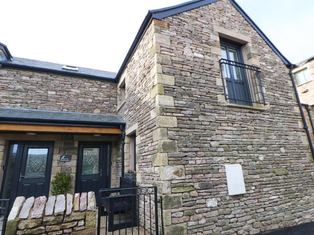 a brick building with a black door and a window at Macaw Cottages, No 4 in Kirkby Stephen