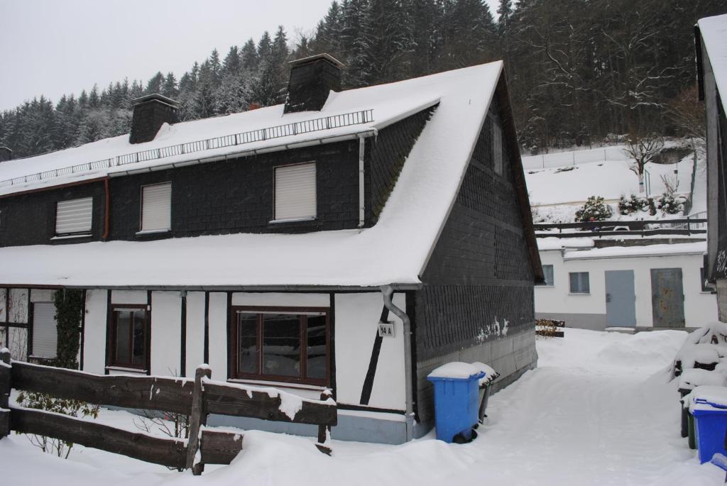 una casa negra con nieve en el techo en Vakantiehuis Ramsbeck, en Ramsbeck