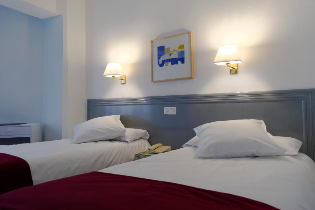 dwa łóżka w pokoju hotelowym z dwoma lampami na ścianie w obiekcie Hotel Vigo Plaza w mieście Vigo