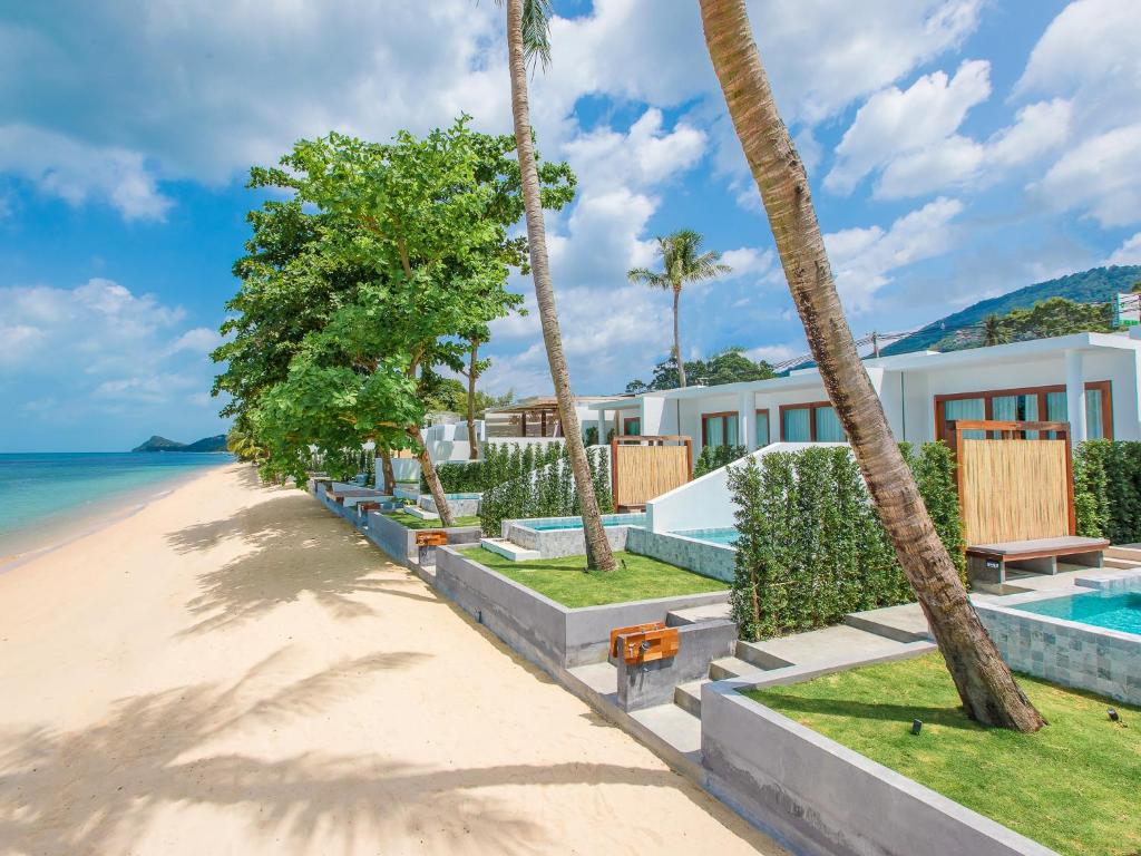 a beach with palm trees and a resort at White Whale Beachfront Pool Villa in Ban Bang Po