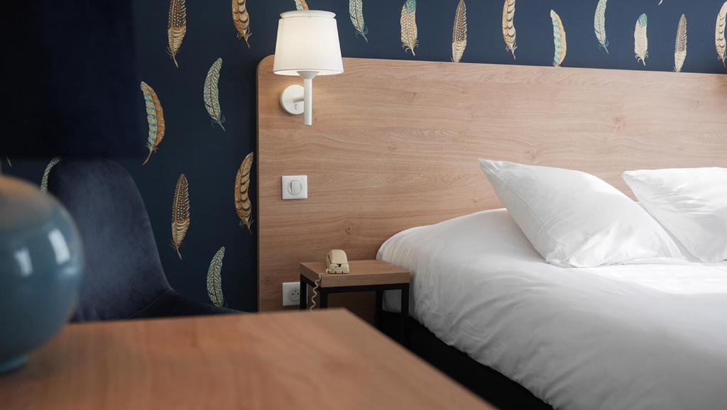 1 dormitorio con cama con almohada blanca y mesa en Logis Saint Louis, en La Suze-sur-Sarthe