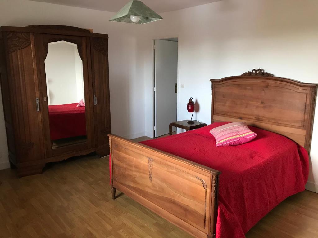 a bedroom with a wooden bed with a red blanket at Ferme de la roque in Millières