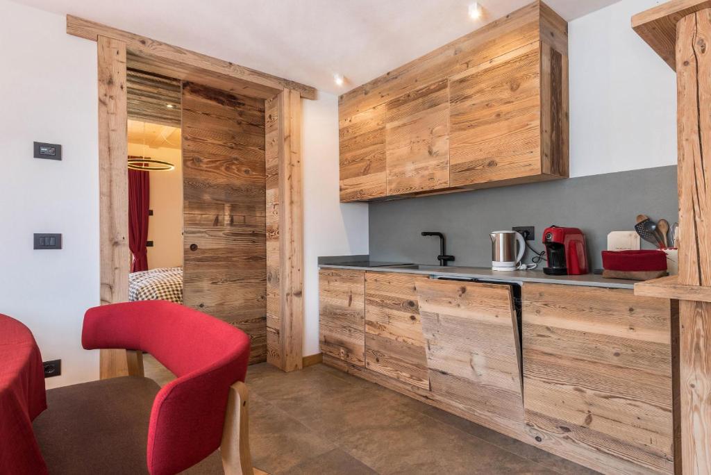 cocina con paredes de madera, encimera y sillas rojas en Majon Baticher, en Canazei