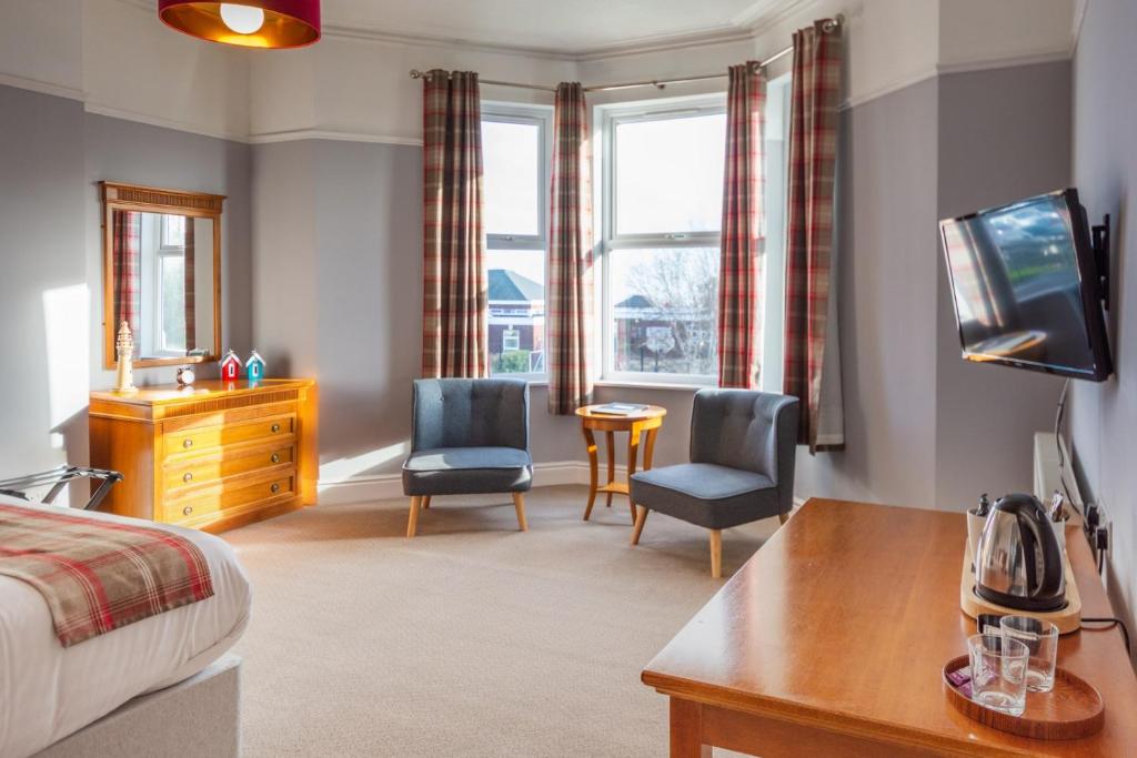 a bedroom with a bed and two chairs and a table at HK Rooms - Self Catering Rooms in Lowestoft