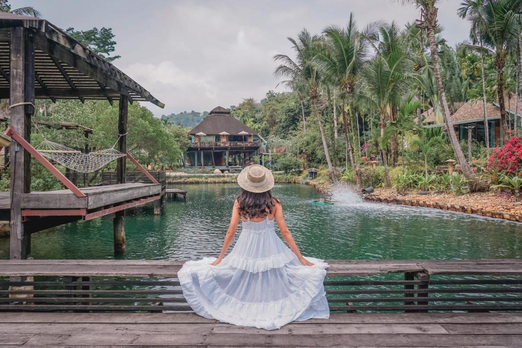 a woman in a white dress sitting on a bridge at The Spa Koh Chang Resort in Ko Chang