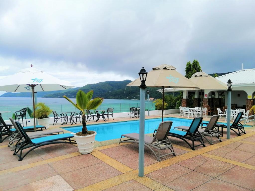 um grupo de cadeiras e guarda-sóis ao lado de uma piscina em Le Relax Hotel and Restaurant em Anse Royale