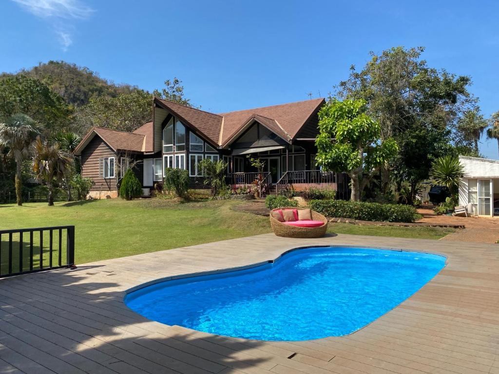 a house with a blue swimming pool in front of a house at Kenora Khaoyai Retreats - Private Pool Villa in Mu Si