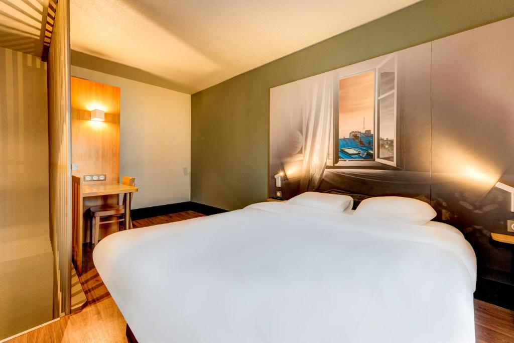 Un pat sau paturi într-o cameră la B&B HOTEL Saint-Witz