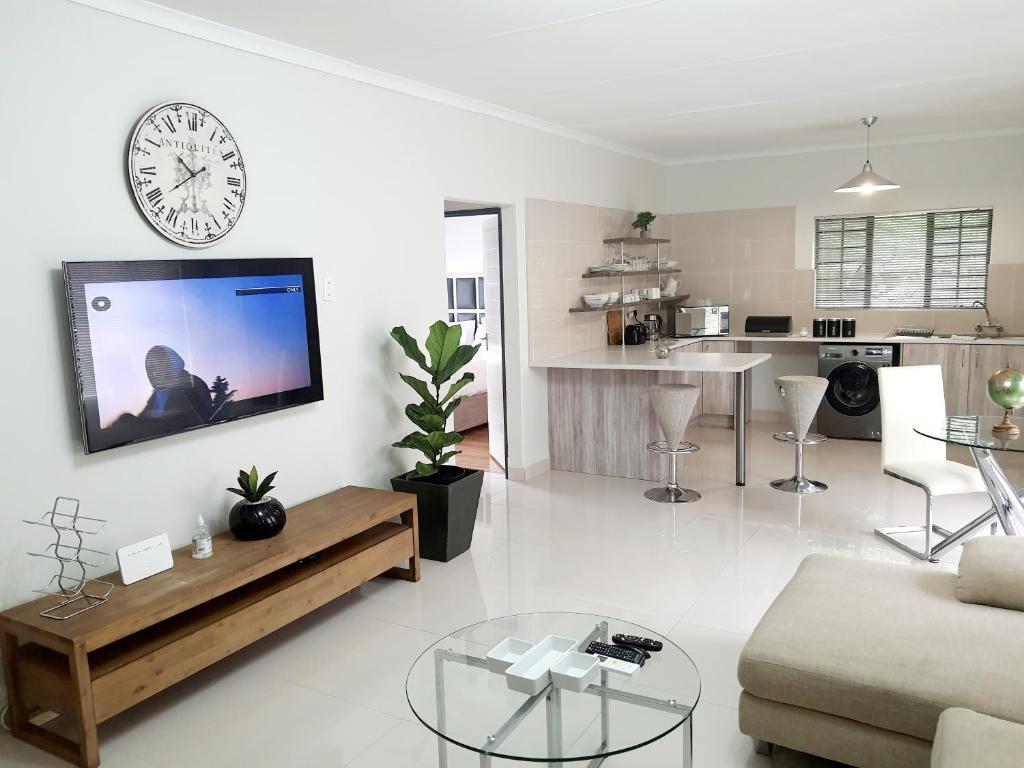 Sala de estar blanca con reloj en la pared en NST City Apartments @ Casalinga Villa en Nelspruit