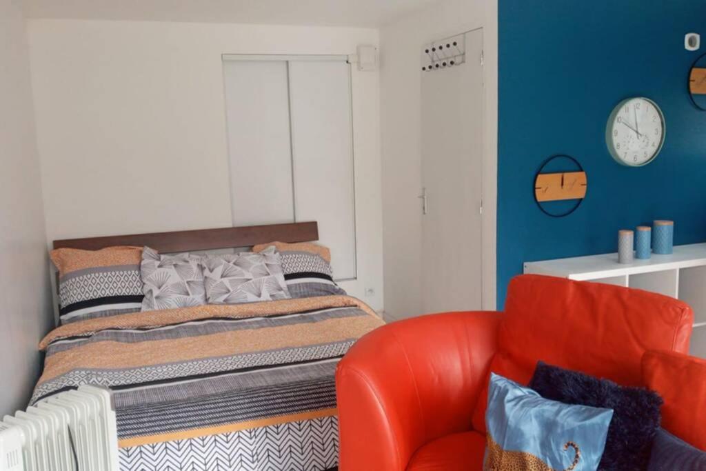 sypialnia z łóżkiem i czerwonym krzesłem w obiekcie Studio de charme pour concentration et détente w mieście Houilles
