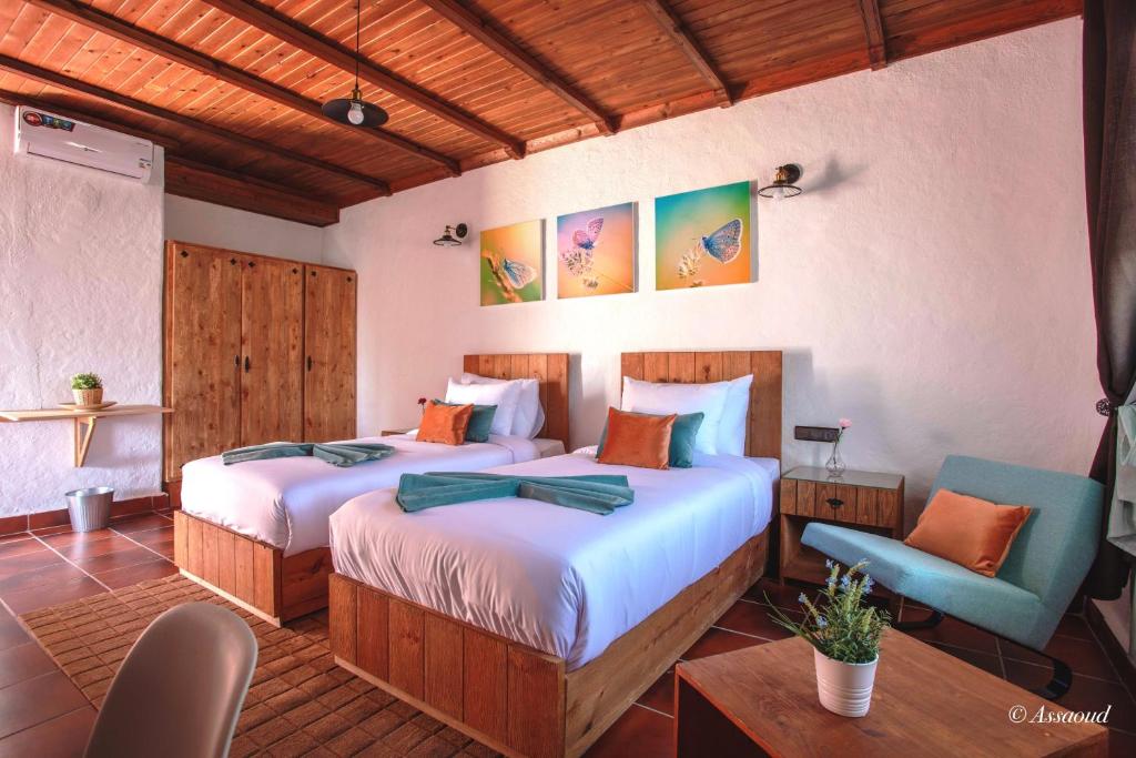 a bedroom with two beds and a table and chairs at Bungalow Double 10 - El Cortijo Chefchaeun Hotel Spa in Chefchaouene