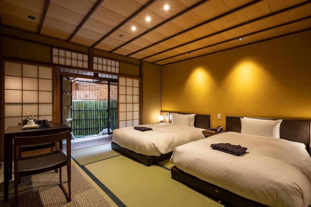 a bedroom with two beds and a desk and a window at 祇園の宿 杏花 in Kyoto