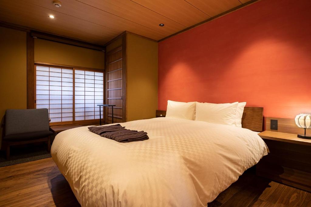 a bedroom with a large white bed with an orange wall at 祇園の宿 杏花 in Kyoto