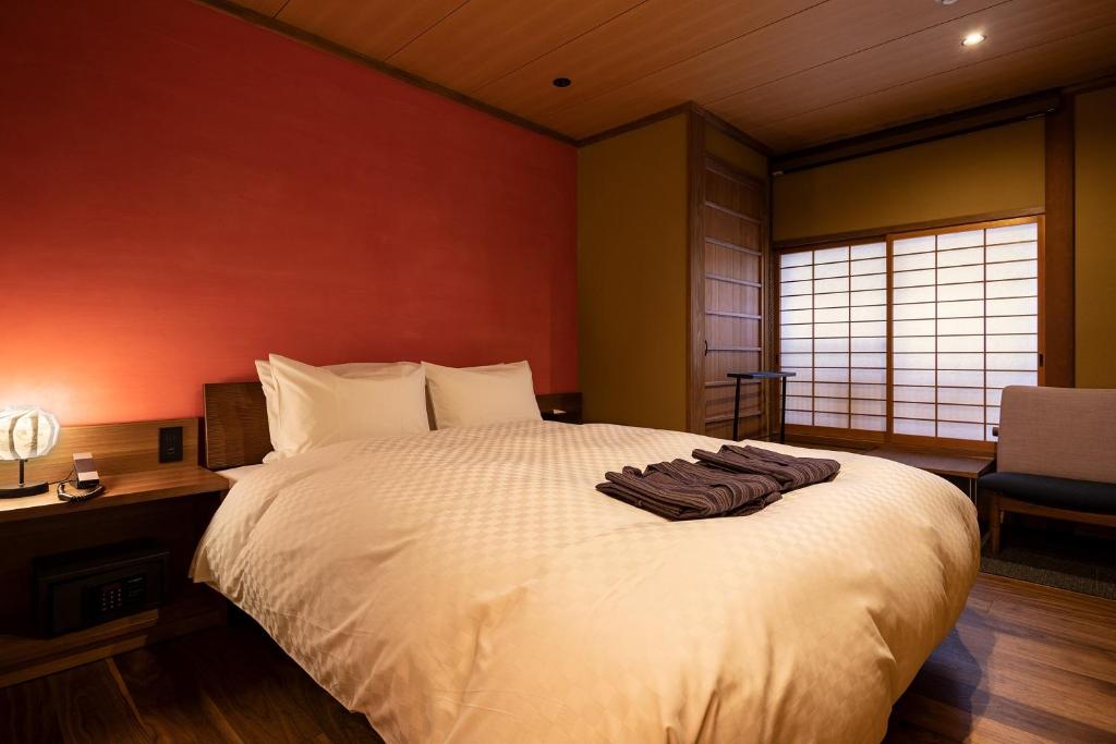 a bedroom with a large white bed and a window at 祇園の宿 杏花 in Kyoto
