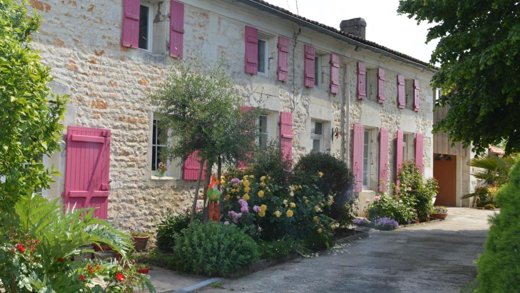 un bâtiment avec des portes roses et des fleurs devant lui dans l'établissement LA PASTORALE, à Beurlay