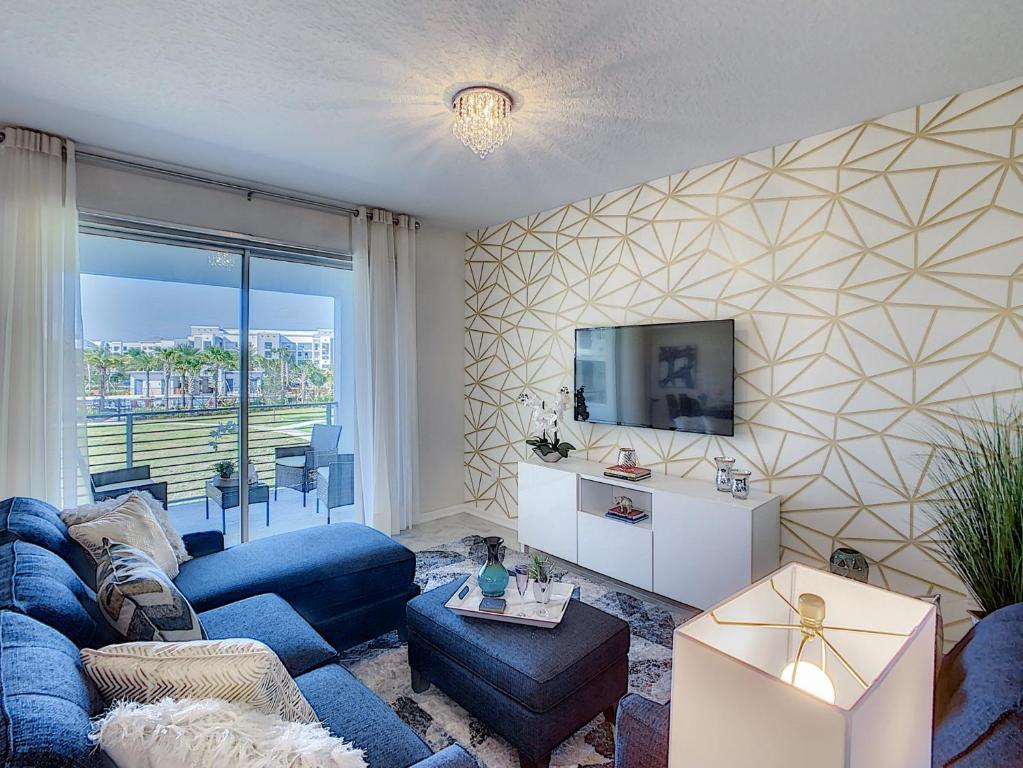 a living room with a blue couch and a tv at Updated Condo, 5 mi to Disney, On-site Water Park in Kissimmee