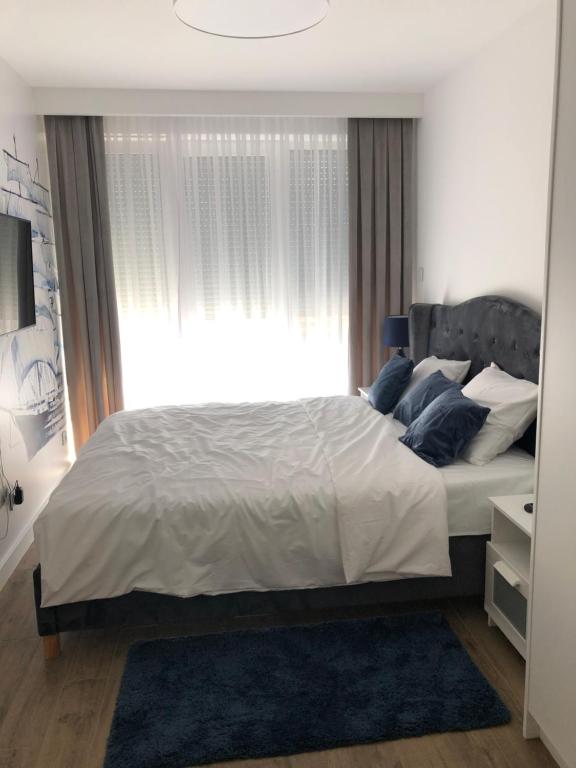 sypialnia z dużym łóżkiem i oknem w obiekcie Apartamenty Klifowa w Rewalu