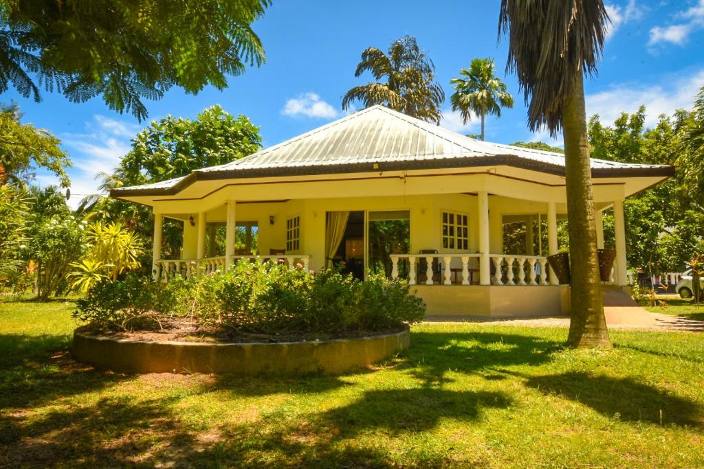 a white house with a palm tree in the yard at Skyblue Guesthouse - Self Catering in Baie Sainte Anne