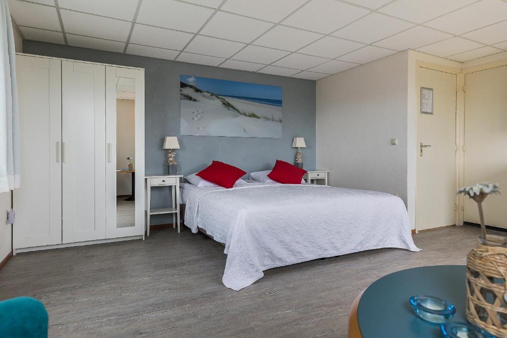 1 dormitorio con 1 cama blanca grande con almohadas rojas en Studio Parkweg, en Bergen aan Zee