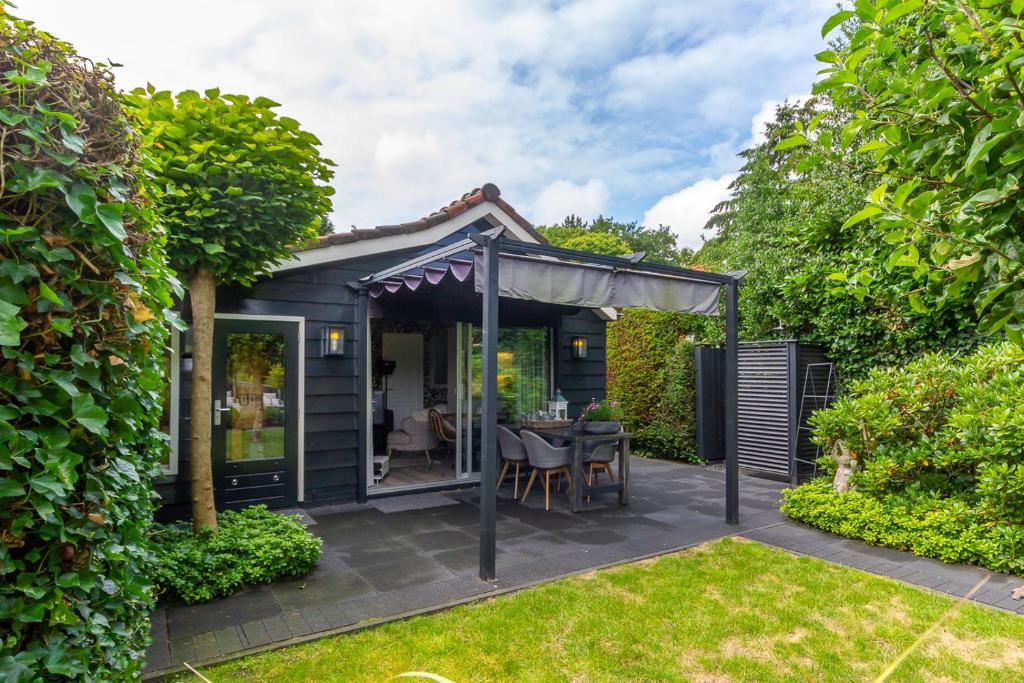 a garden room with a table and a pergola at Vakantiewoning met privé sauna in Schoorl