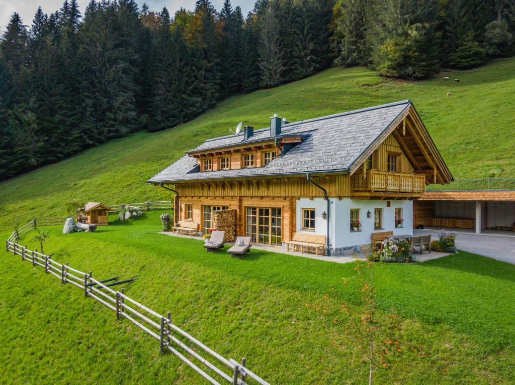 a large wooden house on a hill with a yard at Almchalet Linharterhof in Haus im Ennstal