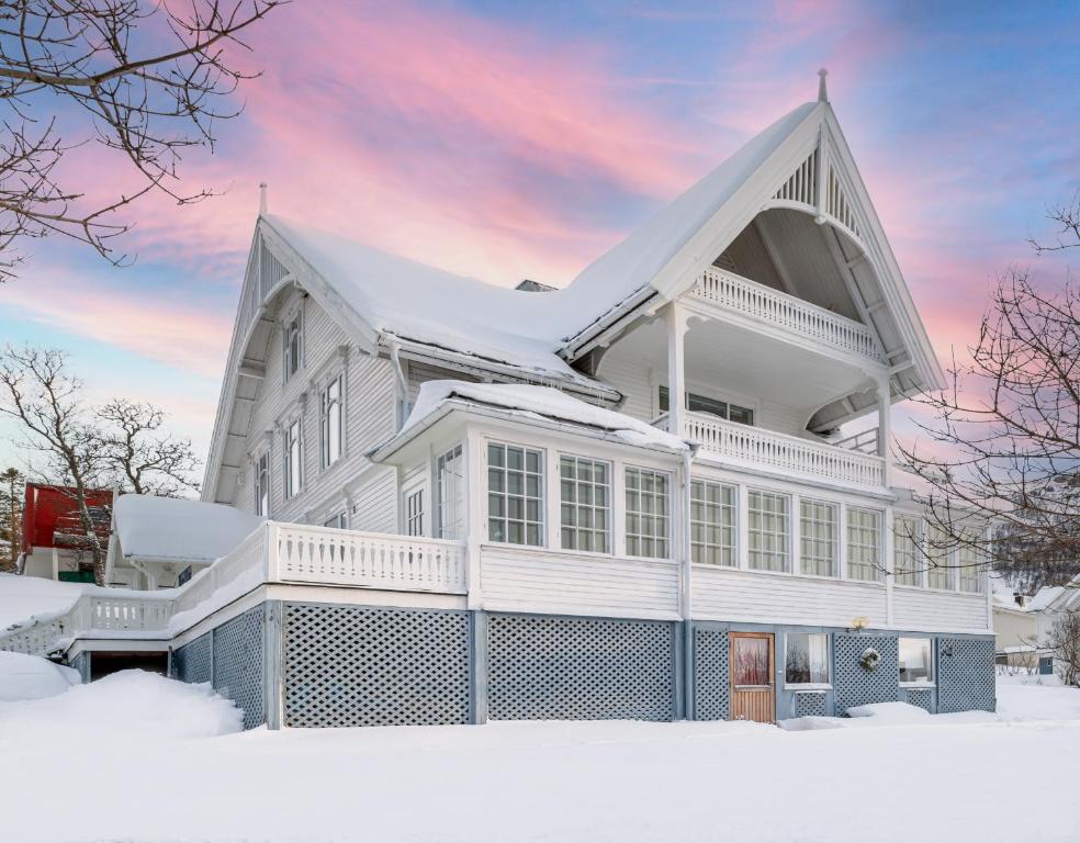 a white house with a steep roof in the snow at The Arctic Villa in Tromsø in Tromsø