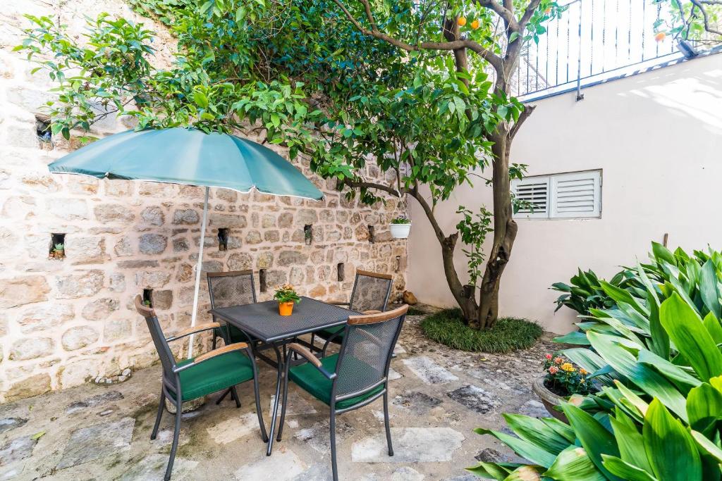 a table and chairs under an umbrella in a courtyard at Apartments Sara in Dubrovnik
