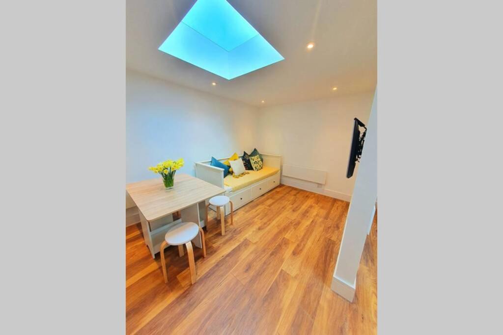 uma sala de jantar com uma mesa e um tecto azul em Cosy detached studio- walking distance to CWOA! em Chessington