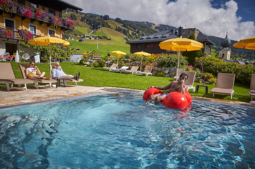 a couple of people in a swimming pool with an inflatable at Hotel Saalbacher Hof in Saalbach-Hinterglemm