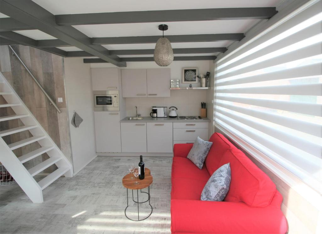 ein Wohnzimmer mit einem roten Sofa und einer Küche in der Unterkunft Casa Paula 2 personen en Casa Christianne 4 personen in Westkapelle