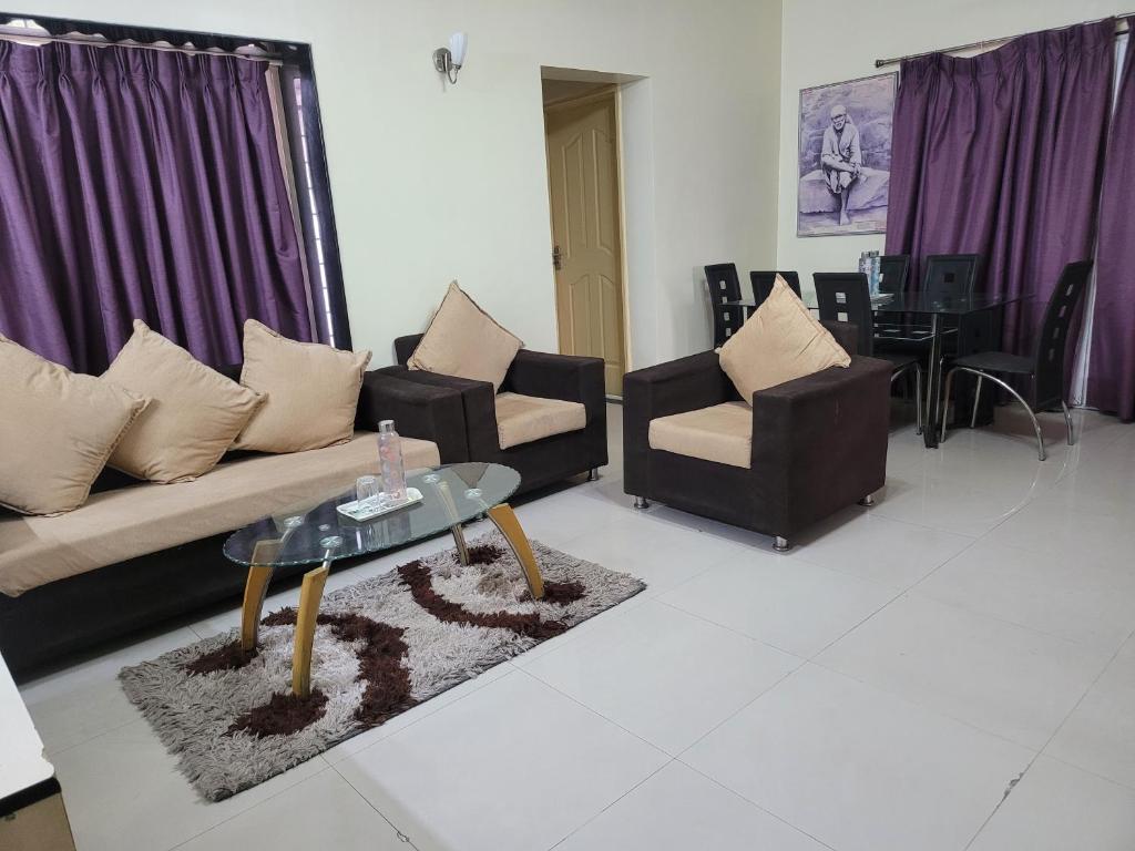 een woonkamer met een bank, stoelen en een tafel bij The Royal Luxury Stay in Pune