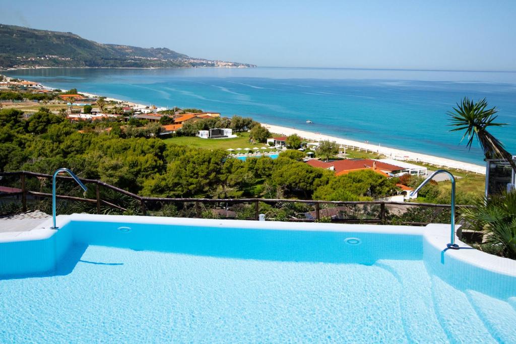 una piscina blu con vista sull'oceano di BV Kalafiorita Resort a Zambrone