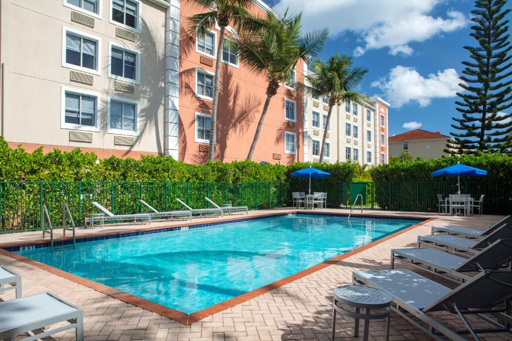 a pool with chairs and umbrellas at a hotel at Baymont by Wyndham Miami Doral in Miami