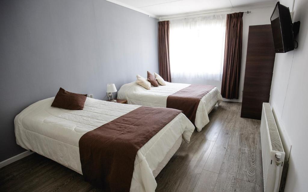 a hotel room with two beds and a window at Hostal Ventisqueros in Punta Arenas