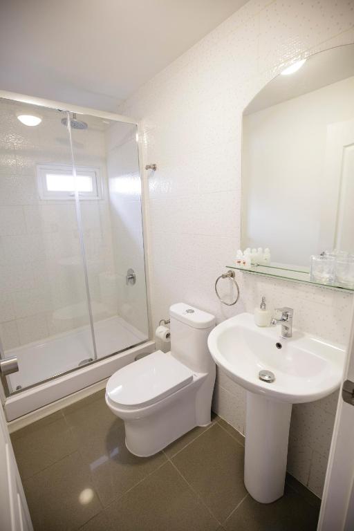 a white bathroom with a toilet and a sink at Hostal Ventisqueros in Punta Arenas