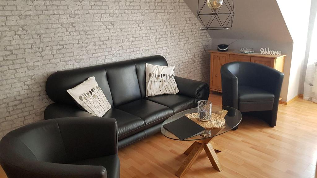 ein Wohnzimmer mit einem schwarzen Ledersofa und 2 Stühlen in der Unterkunft Ferienwohnung Becker in Werdum in Werdum