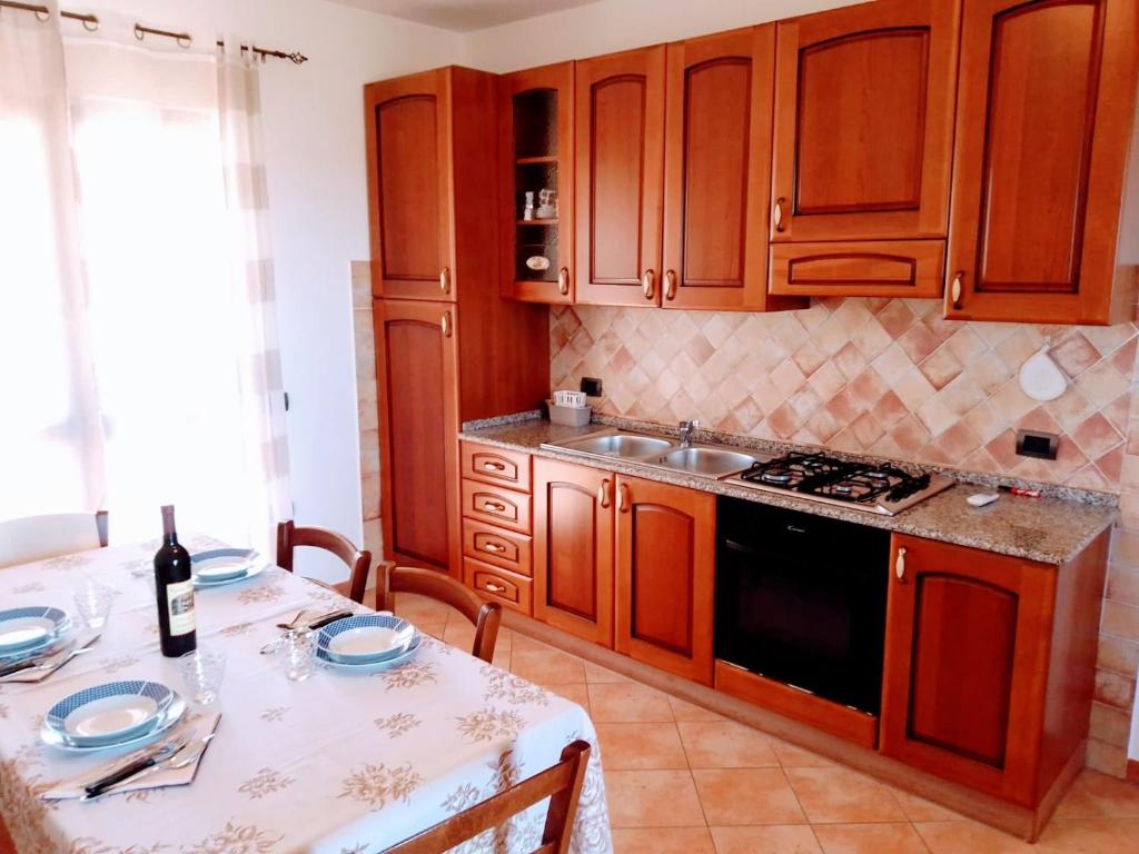 una cocina con armarios de madera y una mesa con una botella de vino en Residenza Rosa Maria, en Orosei