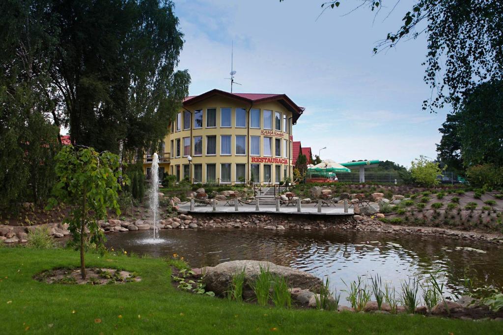 a large building with a pond in front of it at Zajazd KAMA KOWALSKI in Skępe