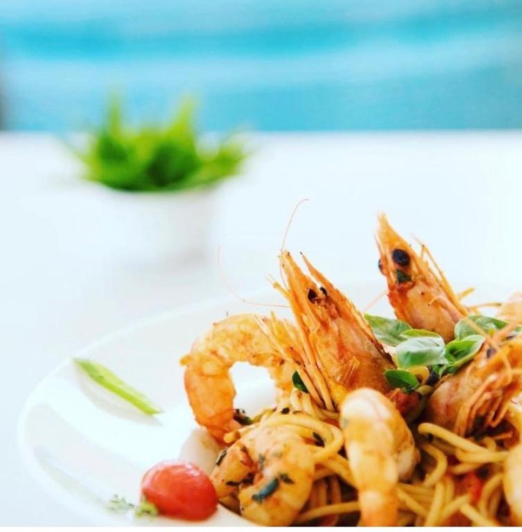 a plate of shrimp and pasta on a table at Fisilanis Beachfront Hotel in Logaras